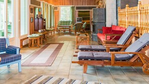 Amplia sala de estar con piso de madera, chimenea y diversas opciones de asientos, incluyendo un sofá, sillas y una zona de descanso con sillones reclinables.