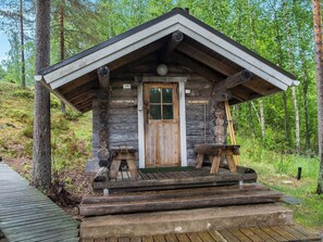 Une cabane rustique avec une porte en bois, un petit porche et une plateforme en béton.