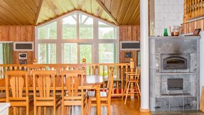 Un interior de madera con techo alto, ventanas amplias, chimenea de piedra y una zona de bar.