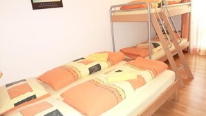 Ein Schlafraum mit Etagenbetten, einem gerahmten Bild an der Wand und Holzboden.