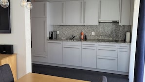 Eine moderne Küche mit grauen Schränken, einer Arbeitsplatte aus Granit und einem eingebauten Backofen.