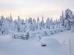 A snow-covered landscape with a wooden fence and trees.