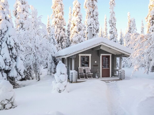 A small cabin surrounded by snow-covered trees.