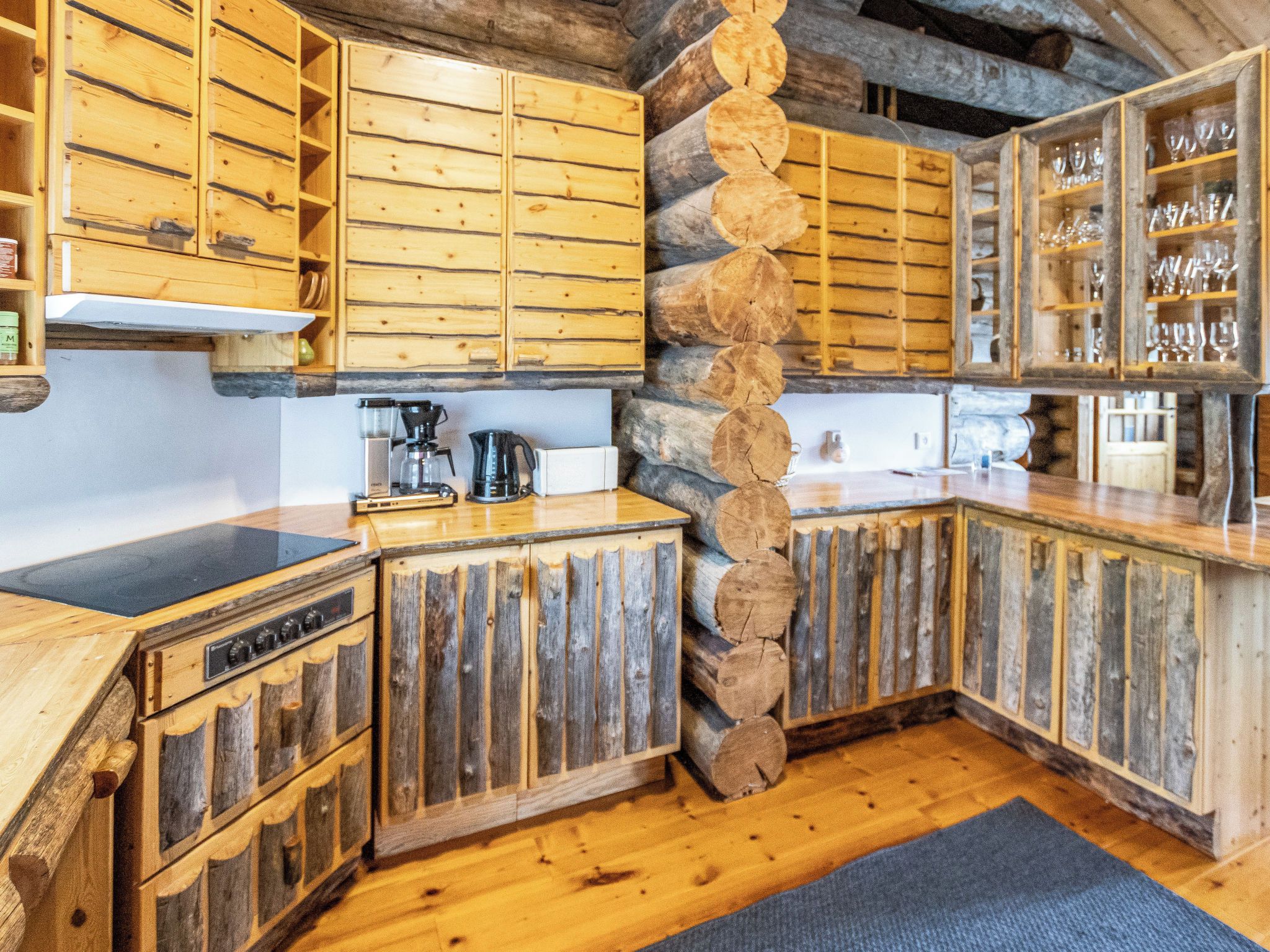 A rustic kitchen with wooden cabinets, a stone wall, and a built-in wine rack.