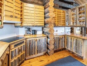 A rustic kitchen with wooden cabinets, a stone wall, and a built-in wine rack.