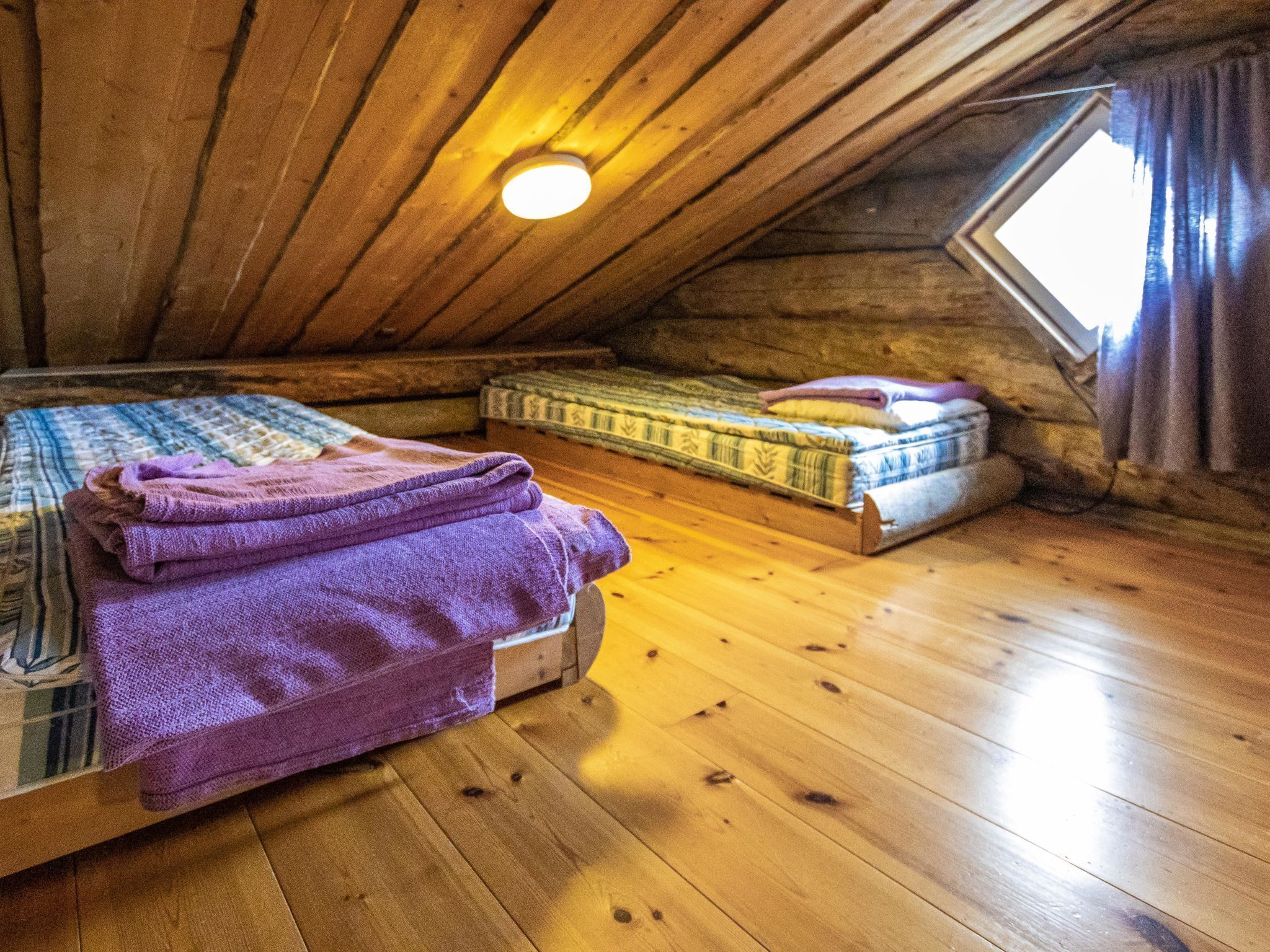 Une chambre mansardée chaleureuse, avec un plancher en bois, un lit superposé et un lit simple.