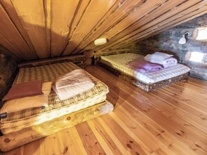 Een knus zolderkamer met twee bedden, houten vloeren en een schuine kap.