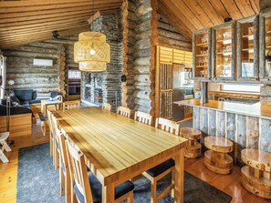 Ein Holzblockhaus-Interieur mit einem großen Holzesstisch, einem Steinkamin und rustikalen Holzmöbeln.