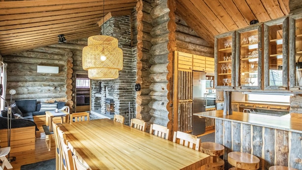 Interior rústico de una cabaña de madera con comedor, cocina y sala de estar.