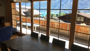 En matplats med ett bord och stolar, stora fönster med utsikt över ett bergigt landskap och en pool.