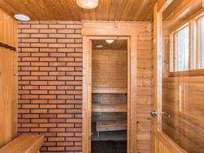 Un sauna en bois avec un mur en briques, un banc et une porte donnant sur un autre espace.