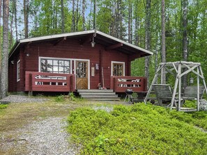 A cabin with a porch, a swing set, and a grill area.