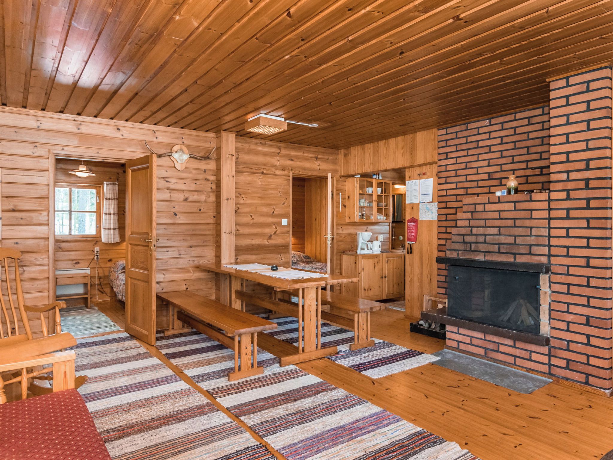 Interior de una cabaña de troncos con chimenea, mobiliario de madera y un comedor.