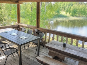 Een houten terras met een tafel en stoelen, uitkijkend op een meer.