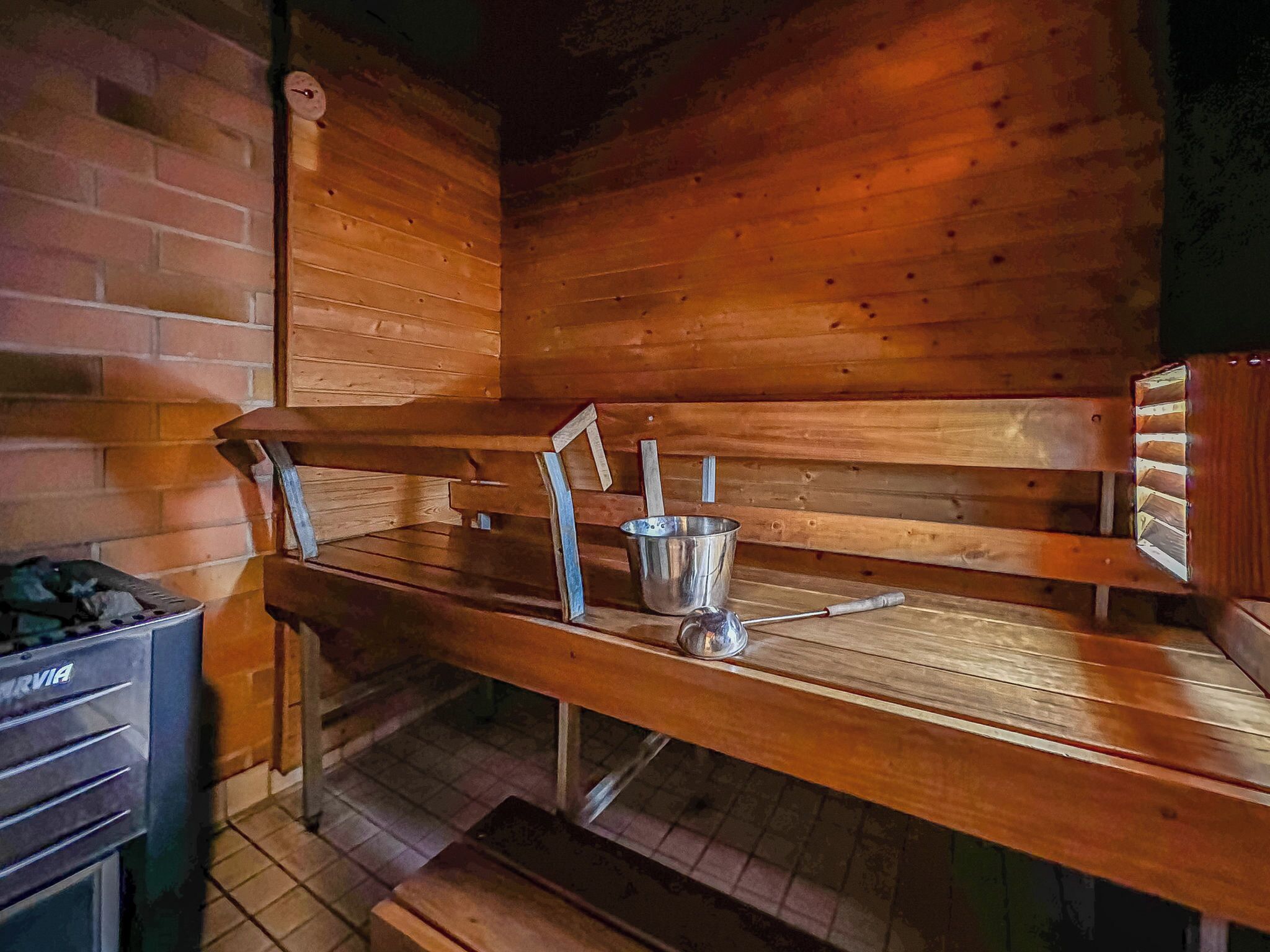 Een sauna met houten banken en een metalen emmer.