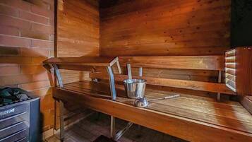 Een sauna met houten banken en een metalen emmer.