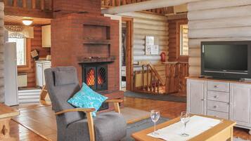 A log cabin interior with a fireplace, a television, a dining area, and a seating area.