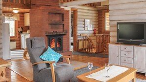 A cozy log cabin interior with a fireplace, a television, a dining table, and a comfortable seating area. - Kalliohonka by Interhome (Hämeenlinna)