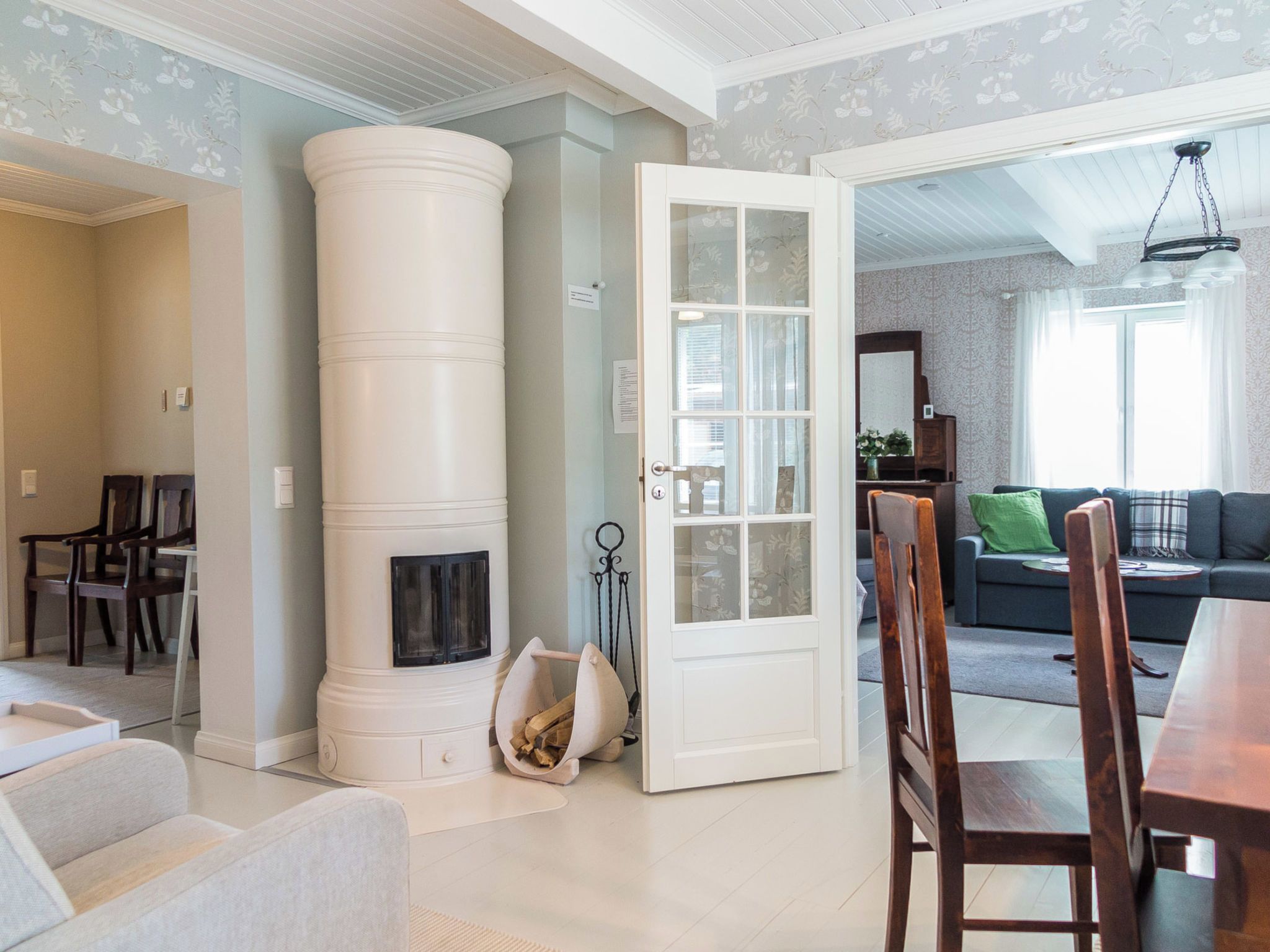 A living room with a white fireplace, a dining area with a wooden table and chairs, and a sofa with a green cushion.