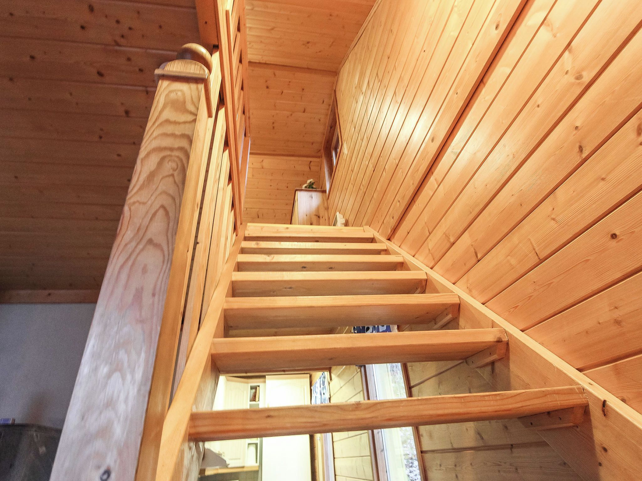 Una escalera de madera con barandilla que lleva a un nivel superior.