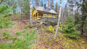 Eine Hütte mit einer Veranda, umgeben von einem Wald.