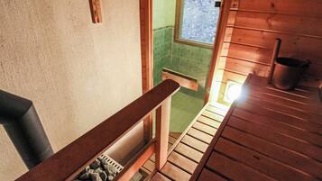 Een houten trap leidt naar een badkamer met een groen betegelde muur en een raam.