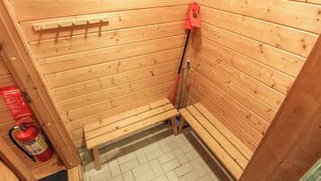 Un sauna en bois, avec des bancs et un extincteur rouge fixé au mur.