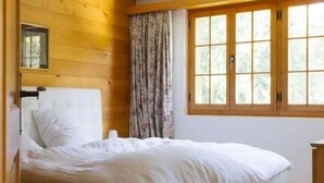 Ein Schlafzimmer mit Holzwand, großem Fenster und einem Bett.