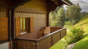 Eine Holzhütte mit einem Balkon mit Blick auf einen üppigen, grünen Hügelhang.