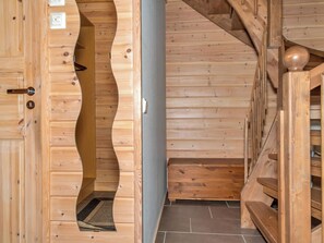 Een houten interieur met een gebogen deur, een trap en een betegelde vloer.
