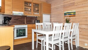 Een moderne keuken met houten kastjes, een eettafel met witte stoelen en een koffieapparaat.
