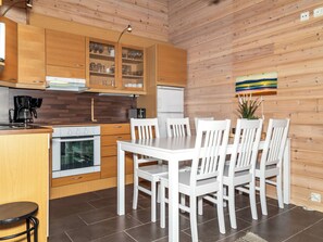Een moderne keuken met houten kastjes, een witte eettafel en stoelen.