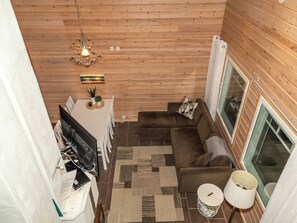 Een gezellig chaletinterieur met houten plafond, een bank, een televisie en een eethoek.