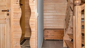 Een houten interieur met een gebogen deur, een trap en een bank.