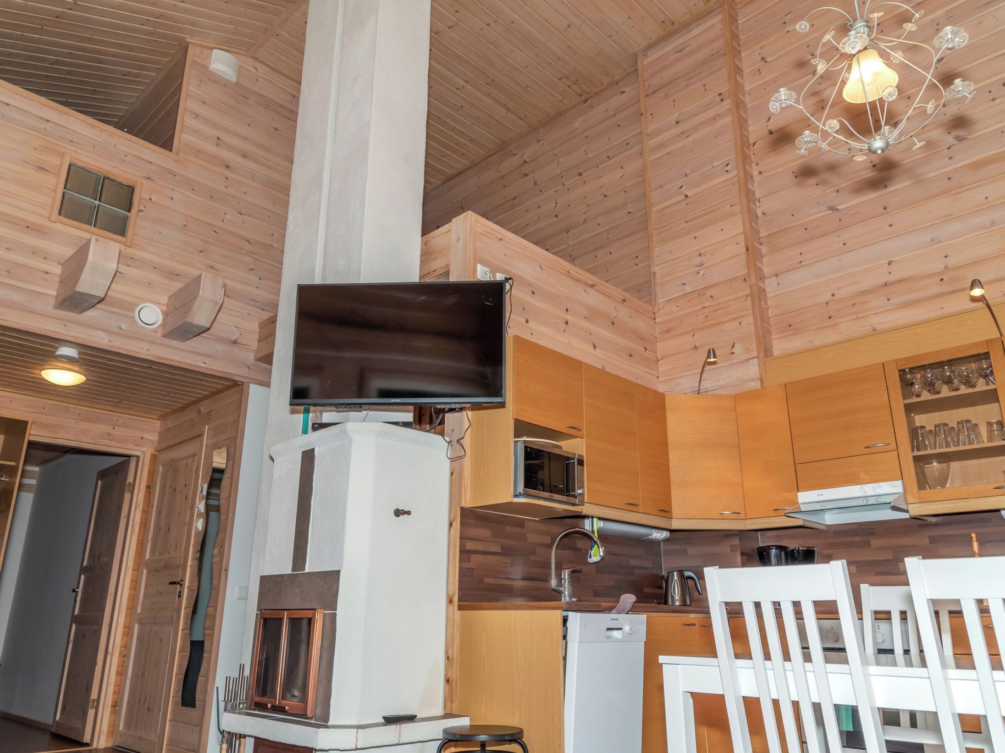 Un interior de madera con chimenea, televisor y comedor con sillas.
