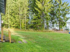 A grassy yard with a wooden deck and a view of a forest and water. - Lomaranta by Interhome (Polvijärvi)