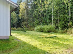 A grassy yard with a white building, surrounded by dense forest. - Lomaranta by Interhome (Polvijärvi)