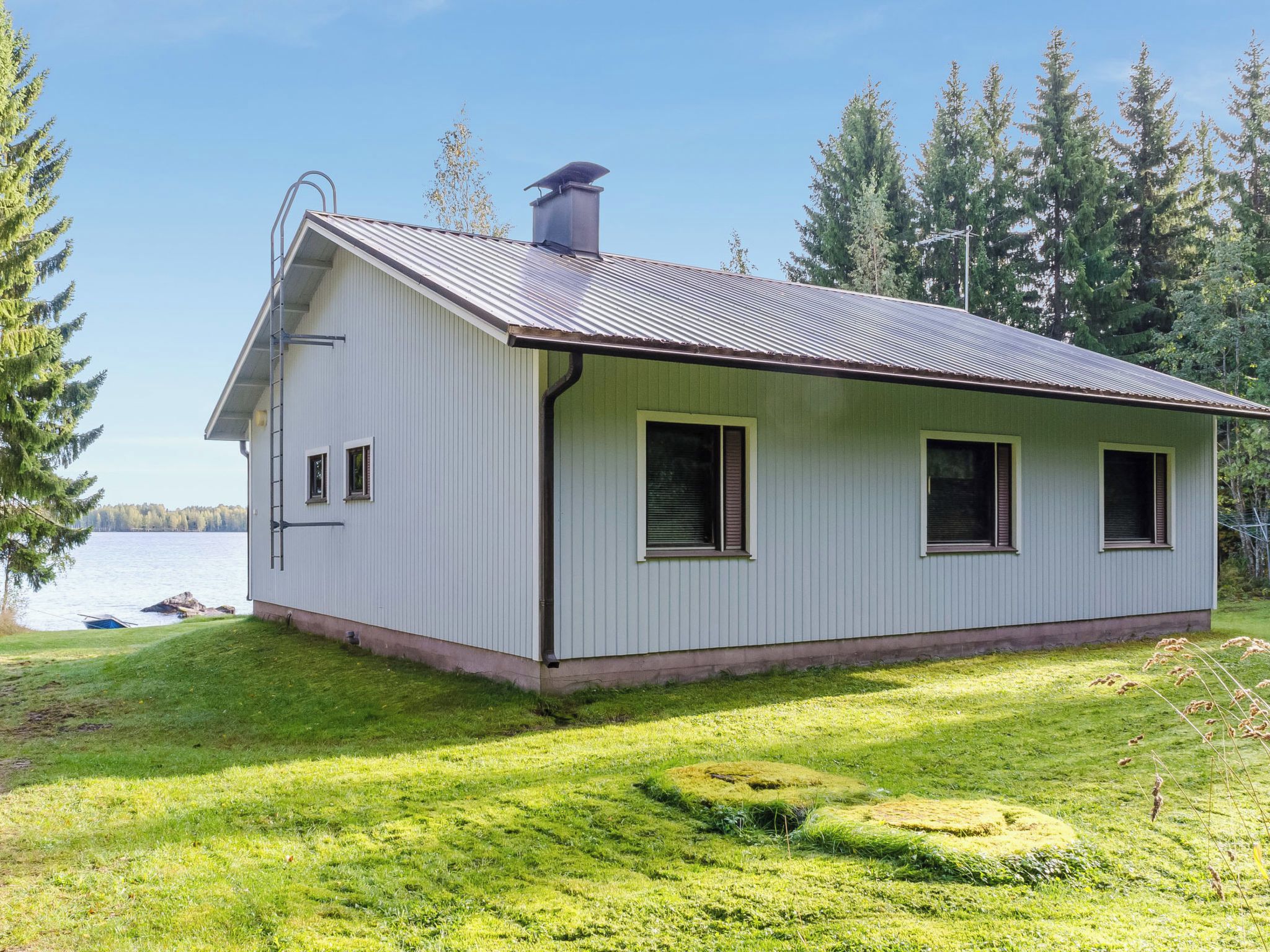 Een gelijkvloers huis met een zadeldak, schoorsteen en een klein portaaltje met een raam.