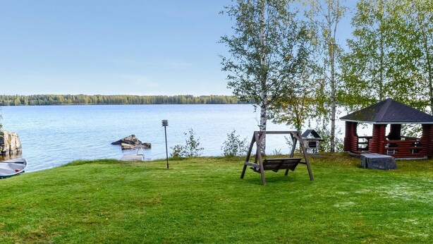 En vacker utsikt över sjön med en trägunga, en lusthus och en brygga med en båt.