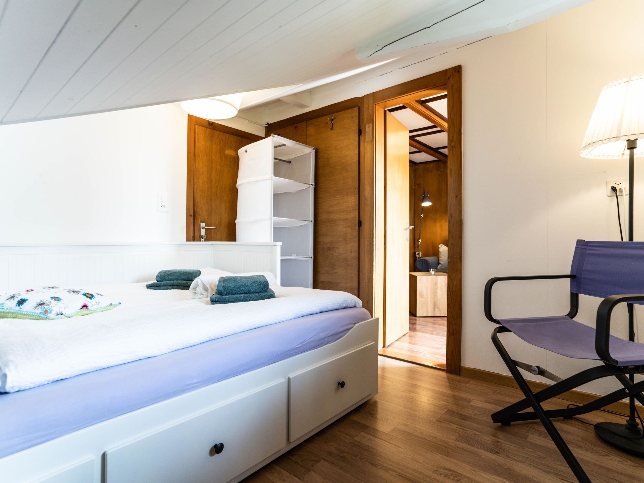 Un dormitorio con cama, una silla y un armario.