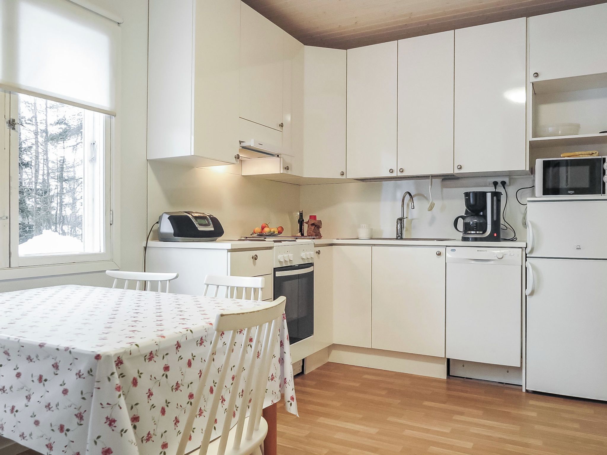 A compact kitchen with white cabinets, a microwave, a coffee maker, and a table with chairs.