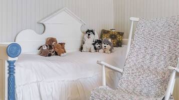 Ein Kinderzimmer mit Bett, Stuhl und Kuscheltieren.