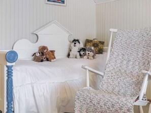 A child's bedroom with a bed, a chair, and stuffed animals.