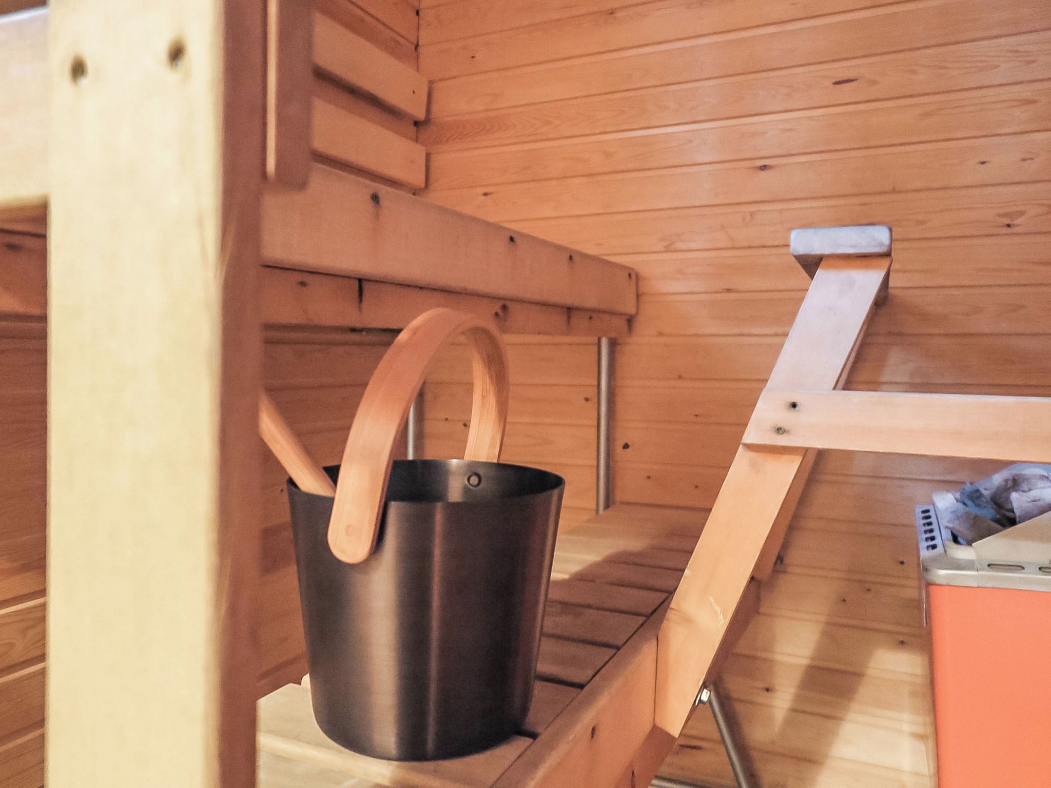 A sauna with a wooden bench and a metal bucket with wooden handles.