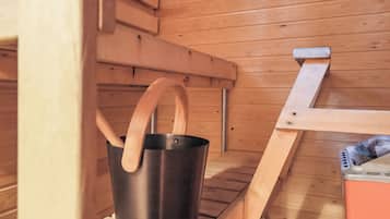 Sauna, jossa on puinen penkki ja metallinen ämpäri, jossa on puukahvat.