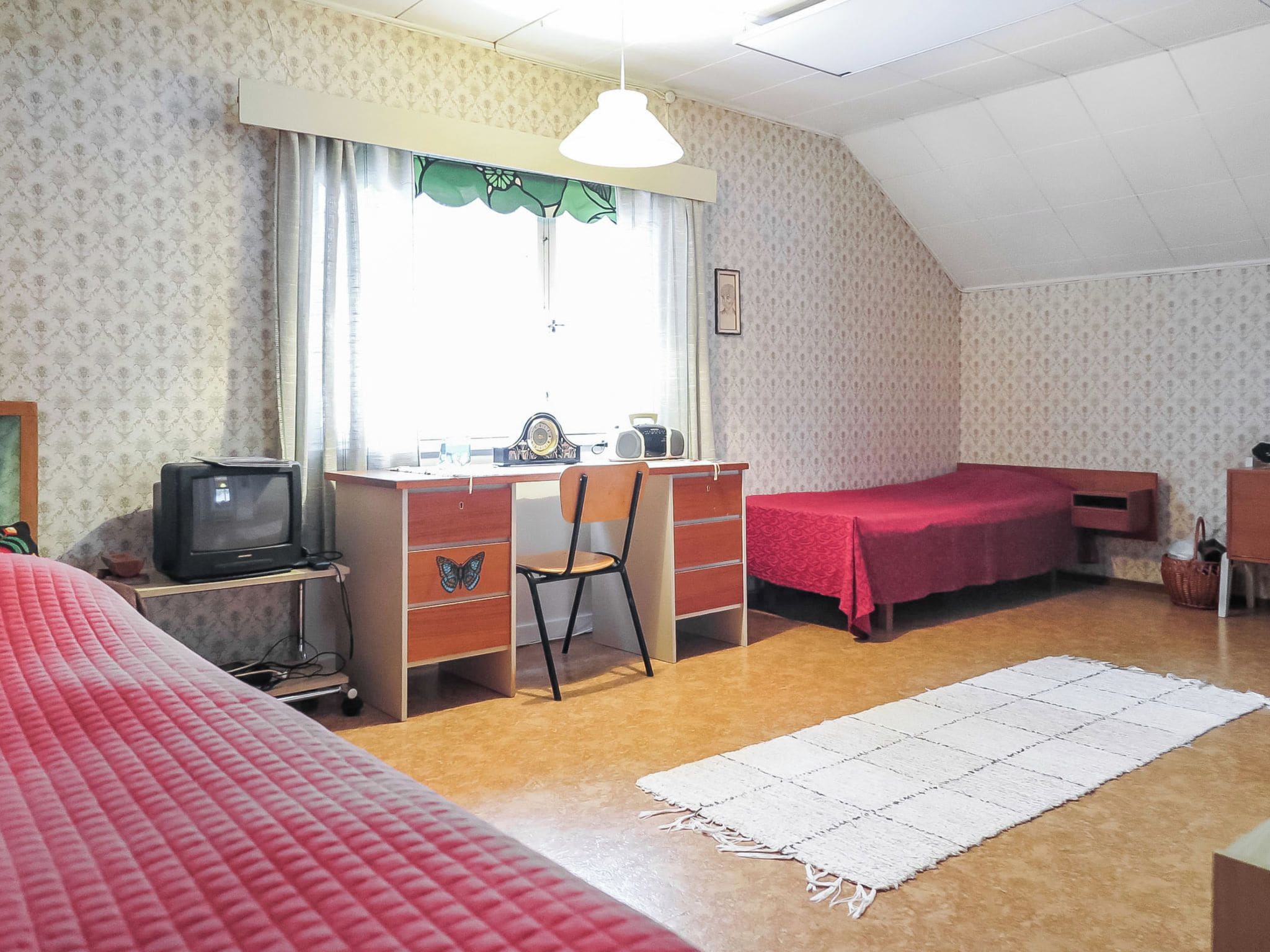 A room with a desk, a chair, a bed, and a window with curtains.