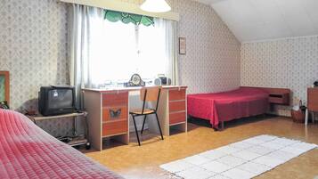A room with a desk, a chair, a bed, and a window with curtains.