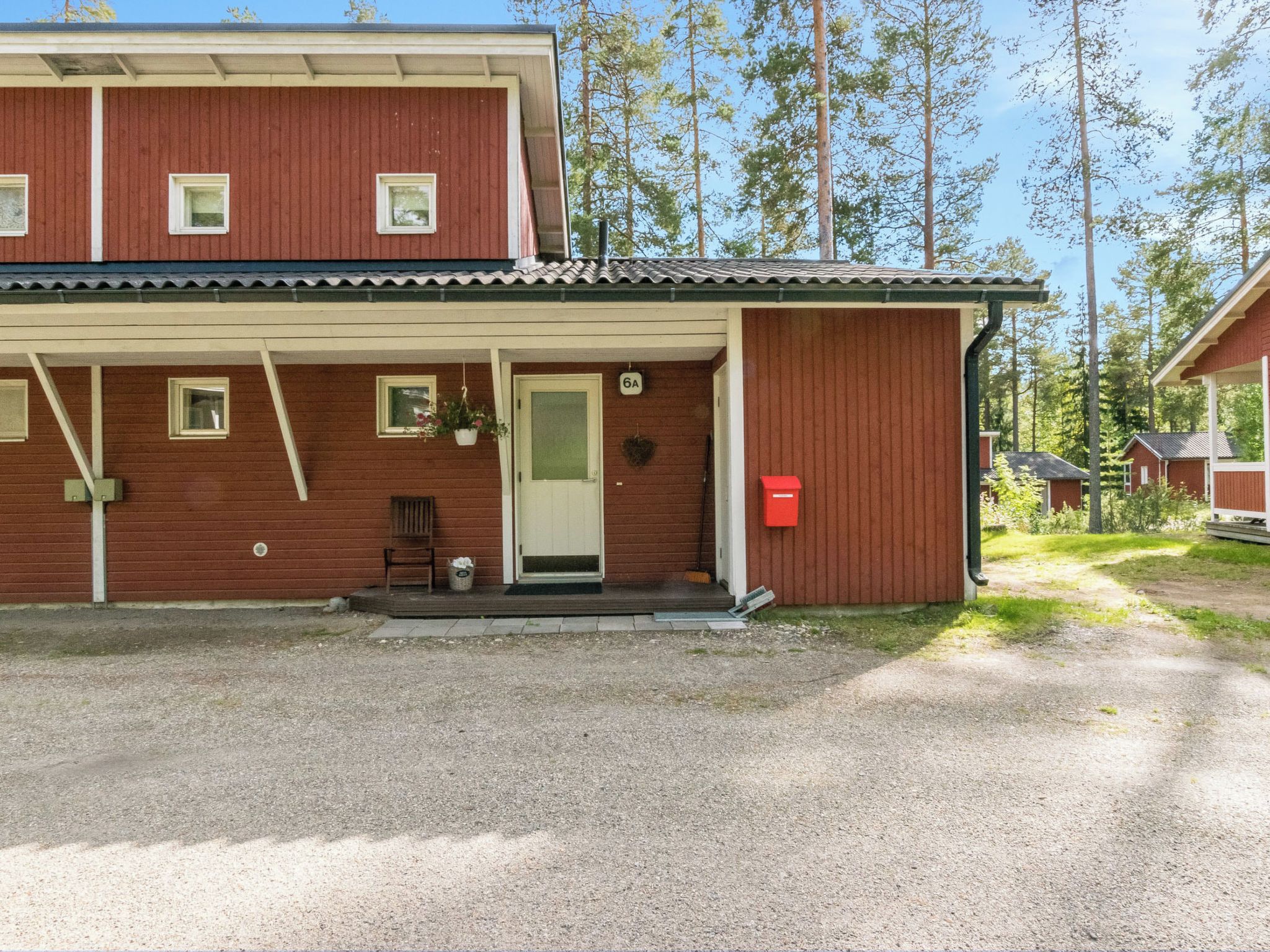 Punaisella julkisivulla varustettu kaksikerroksinen rakennus, jossa on etukuisti ja postilaatikko.