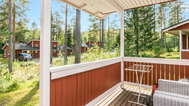 A wooden deck with a white railing, a drying rack, and a wicker sofa.