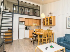 Un espacio habitable compacto con cocina, comedor y una escalera que sube a un nivel superior.